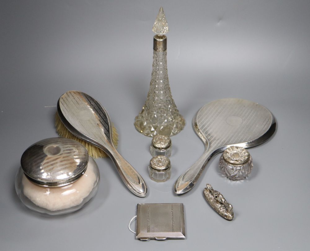 A silver-mounted conical glass scent bottle, sundry other silver-mounted toilet items and an engine-turned silver compact.
